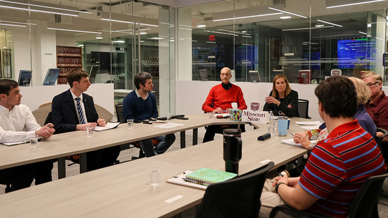 Students seated around table with faculty